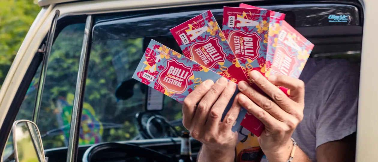 Eintrittstickets aus einem Autofenster gehalten für das Bulli-Summer-Festival