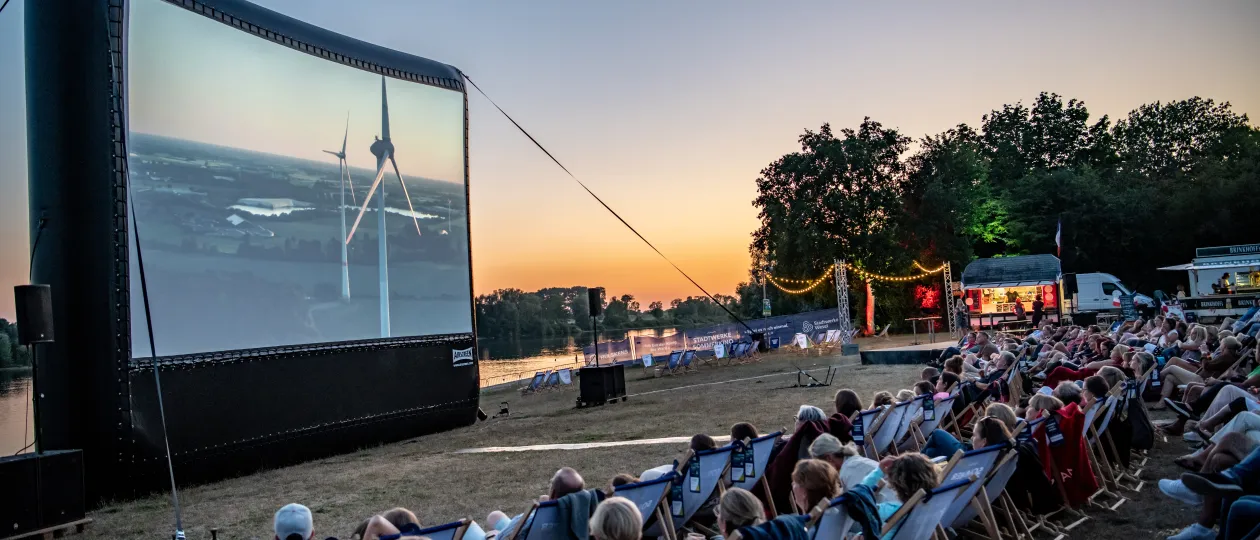 Kinoleinwand und Zuschauende abends am Auesee zum Stadtwerke Sommerkino