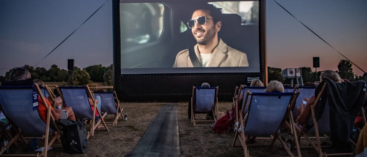 Kinoleinwand und Zuschauende abends am Auesee zum Stadtwerke Sommerkino