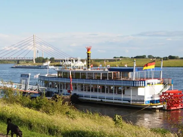Spaziergänger an der Weseler Rheinpromenade mit dem Ausflugsschiff River Lady im Hintergrund