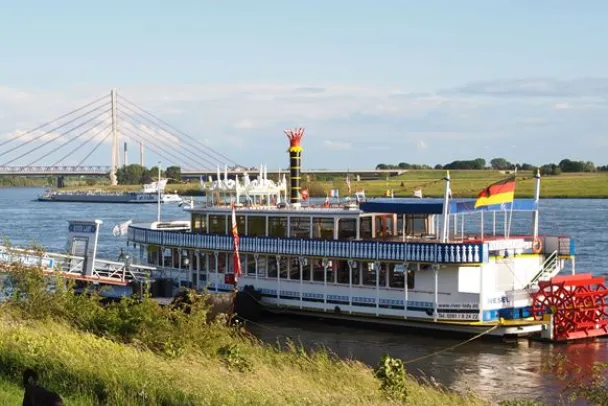 Spaziergänger an der Weseler Rheinpromenade mit dem Ausflugsschiff River Lady im Hintergrund